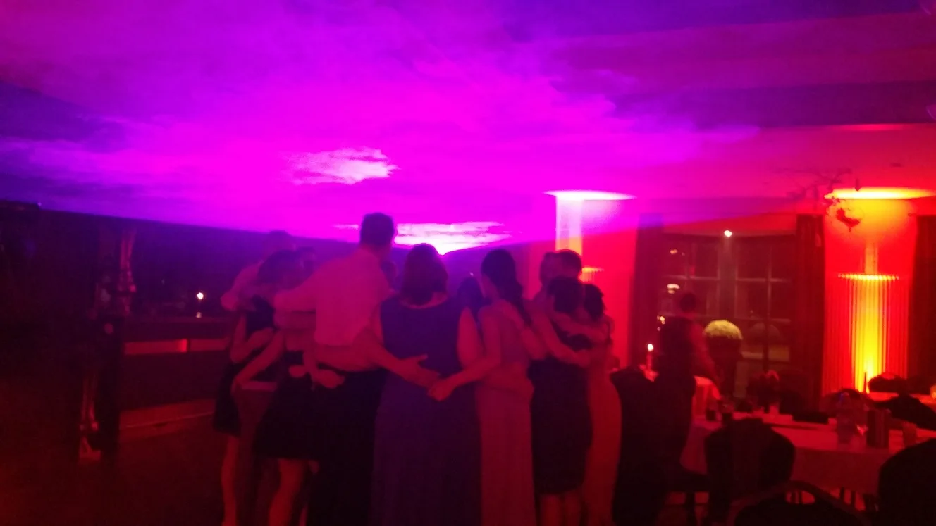 Gästegruppe Arm in Arm bei violettem Ambientelicht