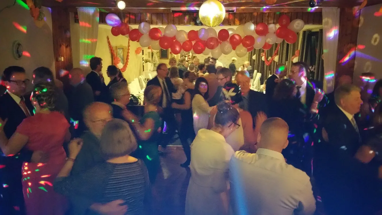 Tanzende Gäste unter Discokugel und Luftballons