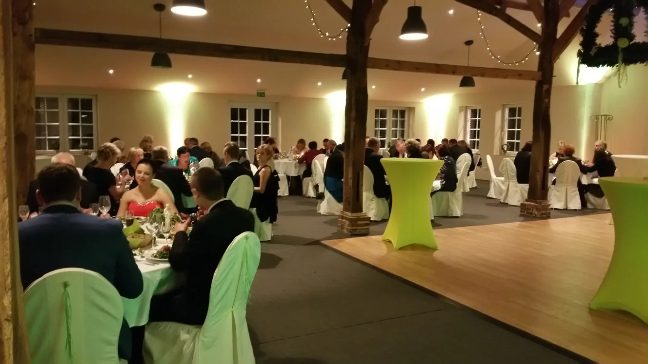 Festsaal mit grün gedeckten Tischen und freier Tanzfläche