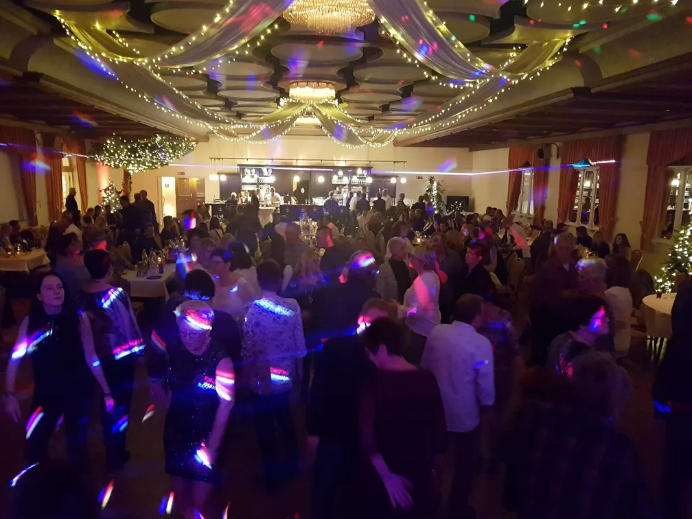 Großer Ballsaal mit Kronleuchtern und tanzenden Gästen