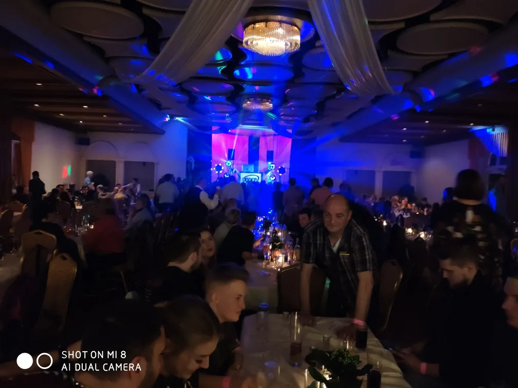 Ballsaal in blauem Licht mit Gästen an den Tischen